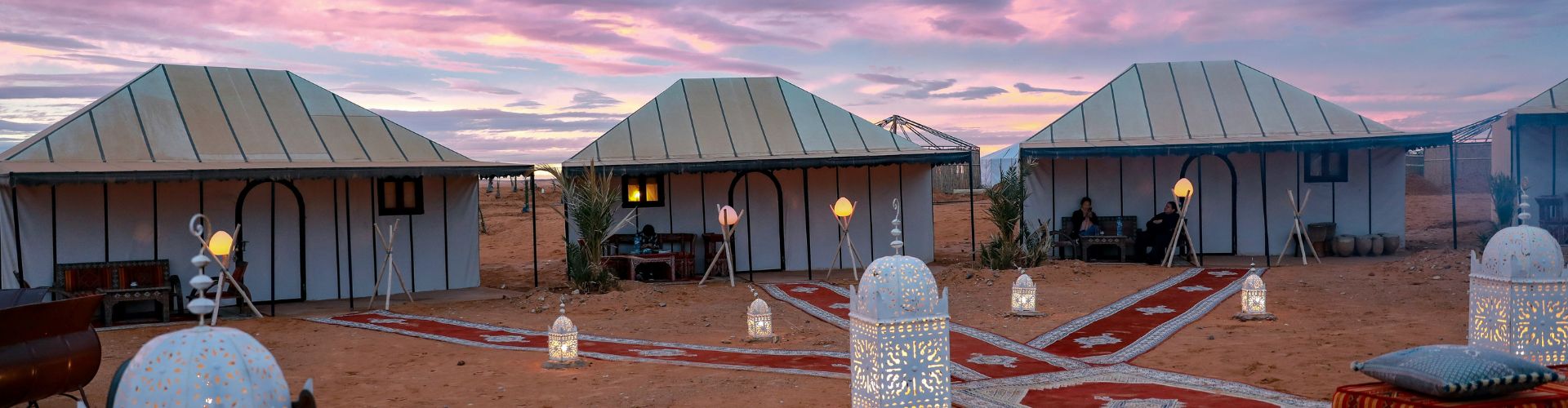 Wildpferde Mongolei Luxuscamp in der marokkanischen Wüste mit Zelten und Laternen bei Sonnenuntergang