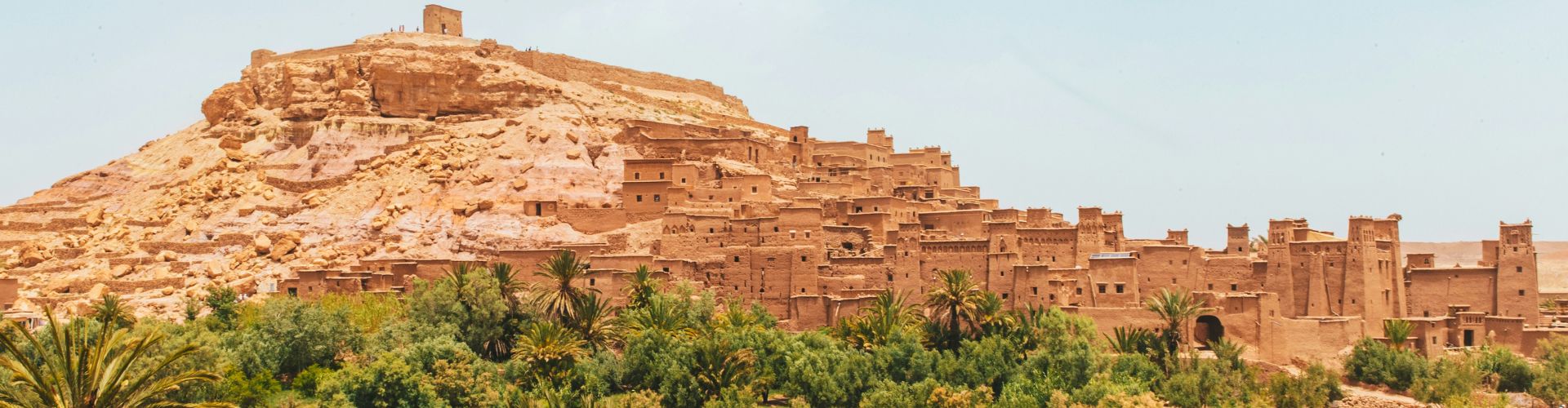 Marokko (2) Lehmfestung Aït Benhaddou in Marokko – historische Kasbah am Berghang vor grüner Palmenoase