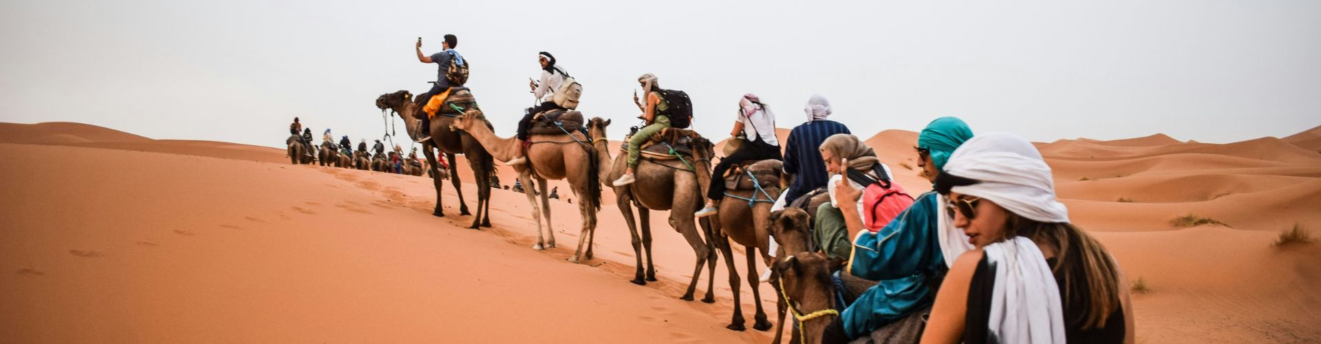 Design ohne Titel (39) Touristen reiten in einer Kamelkarawane durch die Dünen von Merzouga in Marokko.