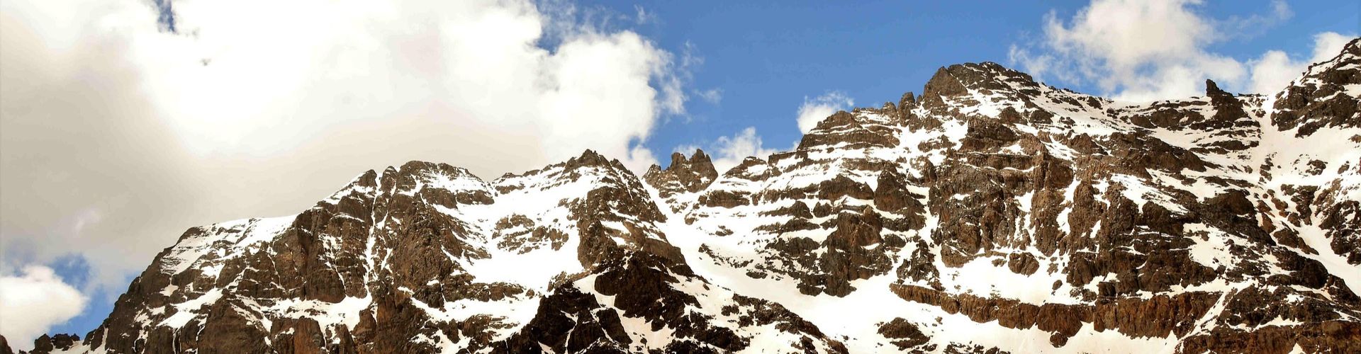 Verschneite Gipfelkette des Djebel Toubkal unter blauem Himmel im Hohen Atlas, Marokko.