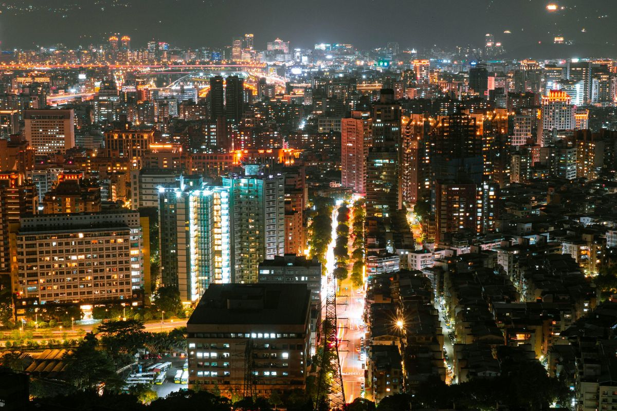 Pulsierende Lichter, Lärm und Energie – der typische Städteurlaub mit Aussicht. Blick über eine hell erleuchtete Großstadt bei Nacht mit Hochhäusern.