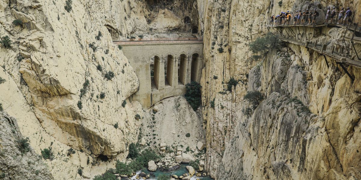 Wanderer auf dem Caminito del Rey mit Blick auf historisches Aquädukt in der Schlucht von Andalusien