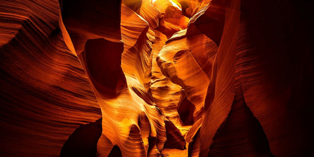 Sonnenstrahlen fallen in den Antelope Canyon und beleuchten die geschwungenen, rot-orangen Sandsteinwände.