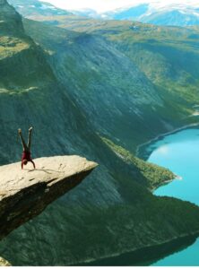 Person macht Handstand auf der Trolltunga in Norwegen, spektakulärer Felsvorsprung über dem Ringedalsvatnet-See