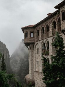 Historisches Meteora-Kloster in Griechenland, das dramatisch auf einer Felsklippe thront, umgeben von Nebel und steilen Schluchten.