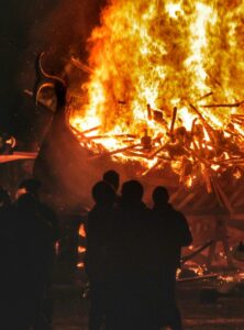 Wikingerfest Up Helly Aa – brennendes Wikingerschiff in der Nacht, Zuschauer silhouettenhaft vor den Flammen.