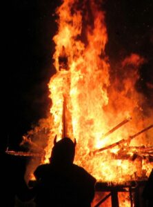 Silhouette eines Wikingers vor dem lodernden Wikingerschiff beim Up Helly Aa Festival auf den Shetland-Inseln.
