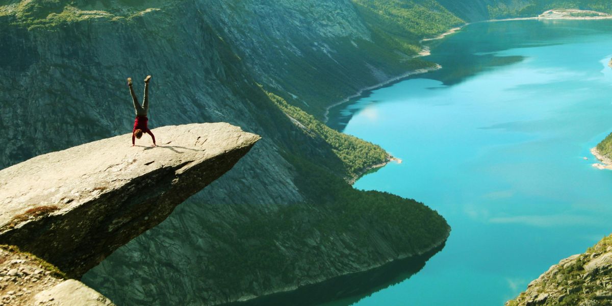 Person macht Handstand auf der Trolltunga in Norwegen, spektakulärer Felsvorsprung über dem Ringedalsvatnet-See